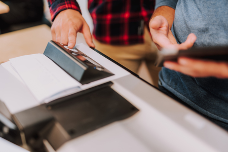 Selective focus of printer touchscreen being used by male colleagues in the office