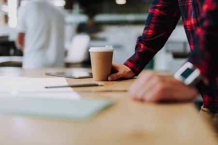 Selective focus of a coffee cup standing on the office table of a modern designerの写真素材