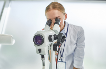 Busy scientist. Portrait of smiling lady in white lab coat doing medical research. Isolated on white backgroundの写真素材