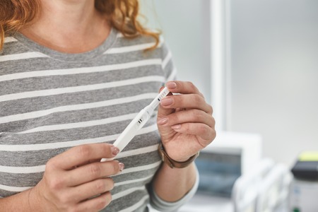I am going to be a mom. Close up of female hands holding positive pregnancy test with two stripes