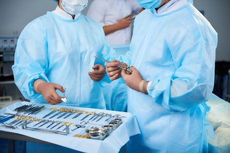 Surgeons working. Smart experienced doctors standing in the operation room and taking necessary instruments for the surgeryの写真素材
