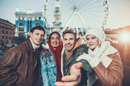 Portrait of cheerful men and satisfied girls hugging while standing near each other during winter holiday outdoorの写真素材