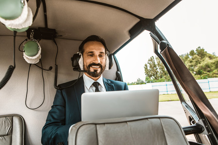 Positive emotional businessman having a productive day and smiling while sitting in the helicopter...