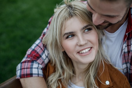 Cheerful mam embracing his beloved lady while she looking at him with wide smileの写真素材