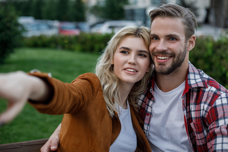 Cheerful young woman embraced by her boyfriend pointing aside. They looking there with bright smileの写真素材