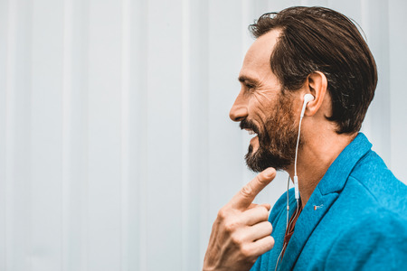Close up of happy young man standing alone and smiling while pointing to the earphones in his earの写真素材