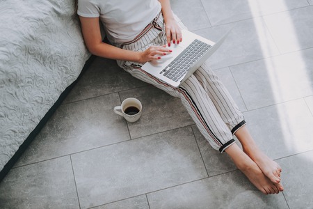 Top view of young woman using her laptop while writing an article at homeの写真素材