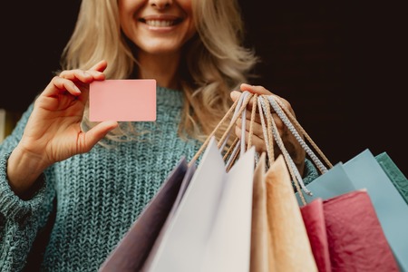 I can buy anything i want. Cropped portrait of smiling middle-aged lady holding pink card and shopping bagsの写真素材
