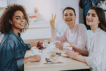 Positive young female friends sitting in the cafe while enjoying time togetherの写真素材