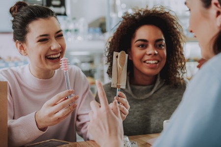 Overjoyed nice woman sitting in the cafe with her friends while showing new baking equipmentの写真素材