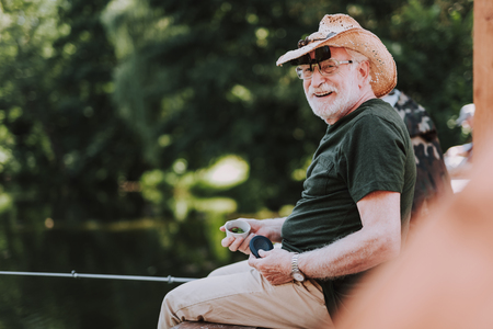 Positive elderly man enjoying his fishing weekend while holdign a rodの写真素材