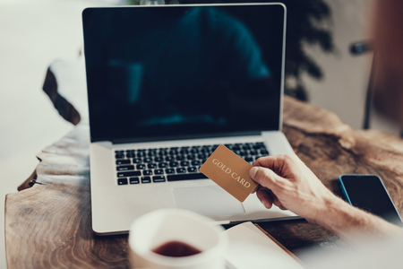 Cropped photo of adult man holding gold bank card in his hand against blurredの写真素材