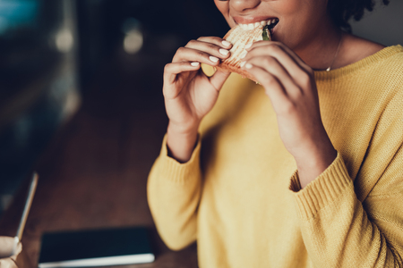 Cropped photo of attractive lady with food. She eating best sandwich in cafe and smilingの写真素材