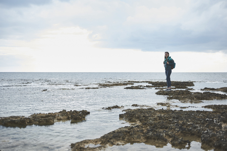 It is time to travel alone. Full length portrait of happy young woman is enjoying her trip with backpack.の写真素材