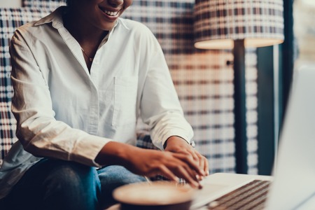 Cropped photo of cheerful woman holding hands on touchpad and smiling. She sitting in cosy cafeの写真素材