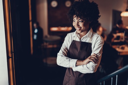 Calm lady folding her hands over chest and looking aside while standing in city cafeの写真素材