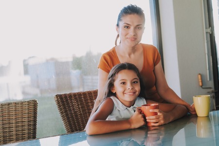 Nice loving woman sitting with her pretty daughter while spending time togetherの写真素材