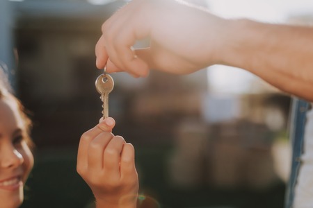 Selective focus of a key held by a pleasant man giving it to his little daughter