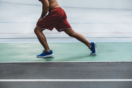 Close up male legs doing physical exercise. He wearing contemporary shorts and sneakersの写真素材