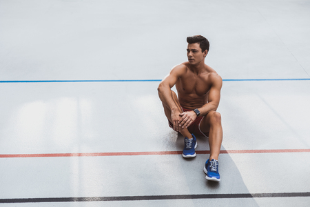 Full length portrait of thoughtful stripped to waist man athlete with attractive body having relax after trainingの写真素材