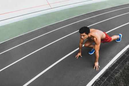 Top view full length portrait of concentrated young male athlete with attractive body wearing shorts clothes during trainingの写真素材