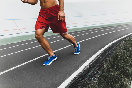 Stripped to waist man running while wearing contemporary sport clothes outdoorの写真素材
