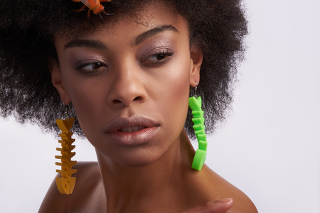 Fashion look and human emotions. Close up portrait of confident afro american female model staying isolated on white background with earringsの写真素材