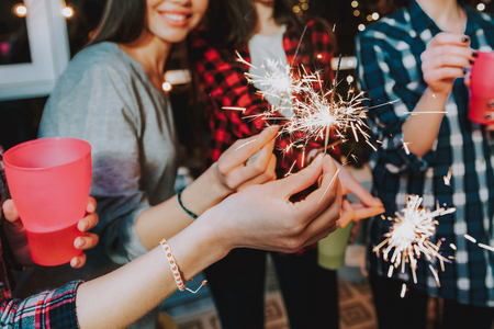 Focus on firework sparkler which smiling girls holding in arms. They celebrating birthdayの写真素材