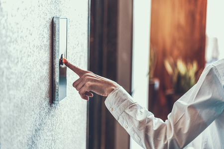 Close up of woman in white shirt standing and pushing the elevator button with her index finger