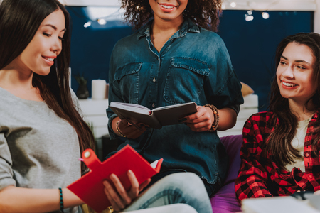 Side view of joyful international female making entries in their diaries. Discussion conceptの写真素材