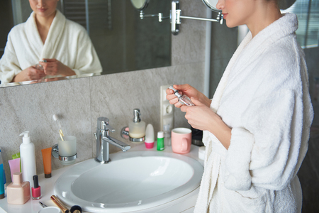 Young lady holding bottle of perfume in handの写真素材