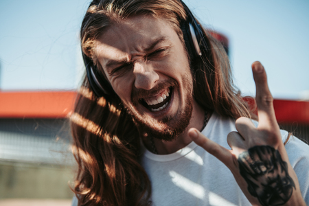 Overjoyed nonconformist man is enjoying rock musicの写真素材