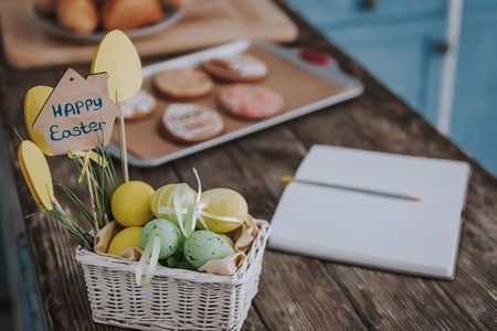 Opened copybook and colorful Easter eggs on table