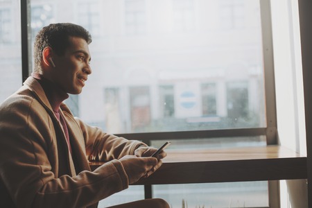 Handsome young man using cellphone and wireless earphonesの写真素材