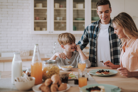Happy family in the kitchen having breakfast and smilingの写真素材