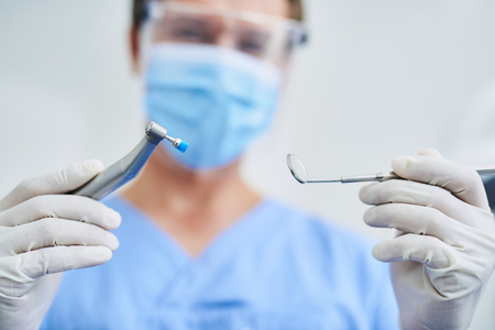 Male dentist in sterile gloves demonstrating dental toolsの写真素材