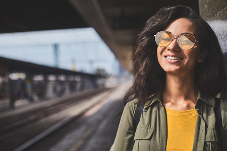 Stylish attractive woman in colored sunglasses with railway on background