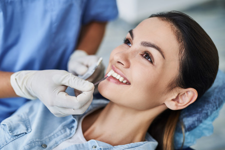 Dentist choosing color of teeth for young woman