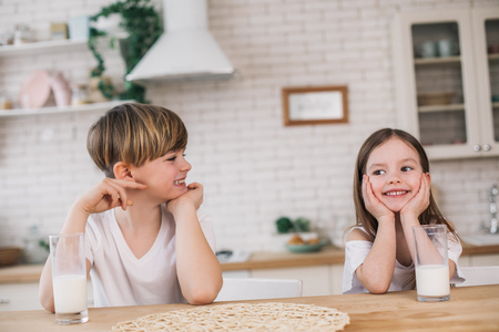 Half length of smiling children sitting at table in grannys houseの写真素材
