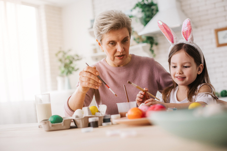 Cropped photo of gray-haired woman talking to little girl at tableの写真素材