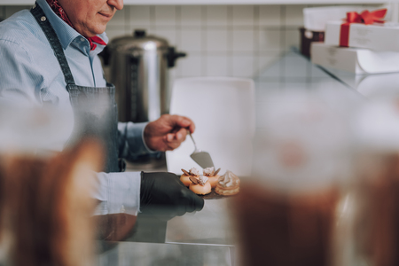 Gentleman in apron preparing delicious pastries for special orderの写真素材