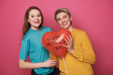 Waist up of happy brown-haired girl congratulating her mother with holidayの写真素材