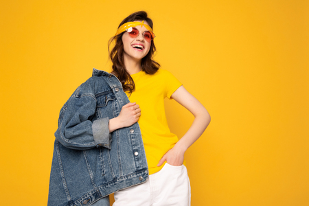 Cheerful hipster girl posing isolated on yellowの写真素材