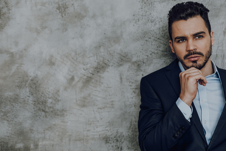 Pensive businessman in elegant clothes against grey wallの写真素材