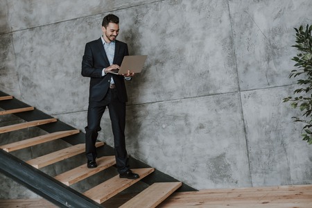 Jolly man with laptop going on stairwell