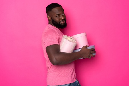 Unhappy African man keeping gifts and looking at camera in studio
