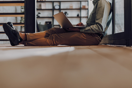 Man is working on notebook while being on floorの写真素材