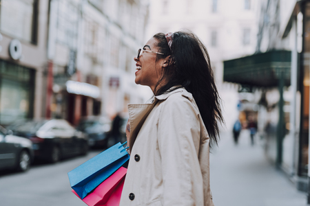 Charming afro american lady with shopping bags standing on the streetの写真素材