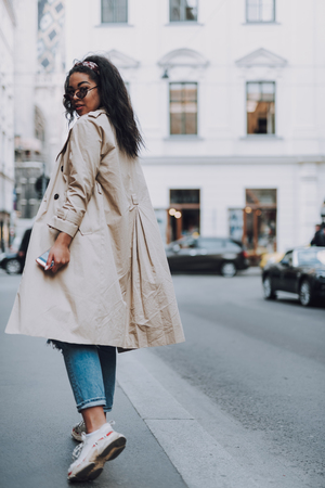 Attractive afro american girl with cellphone walking on the streetの写真素材