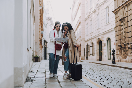 Two beautiful young women looking at map on the streetの写真素材